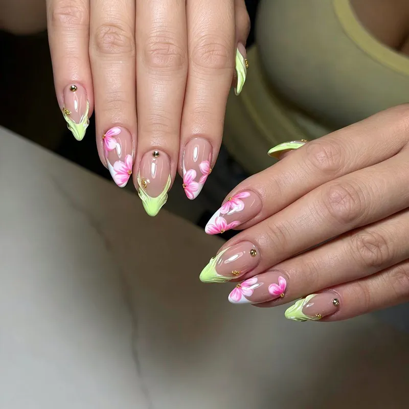 Nude almond nails with lime green French tips, pink flowers and gold studs